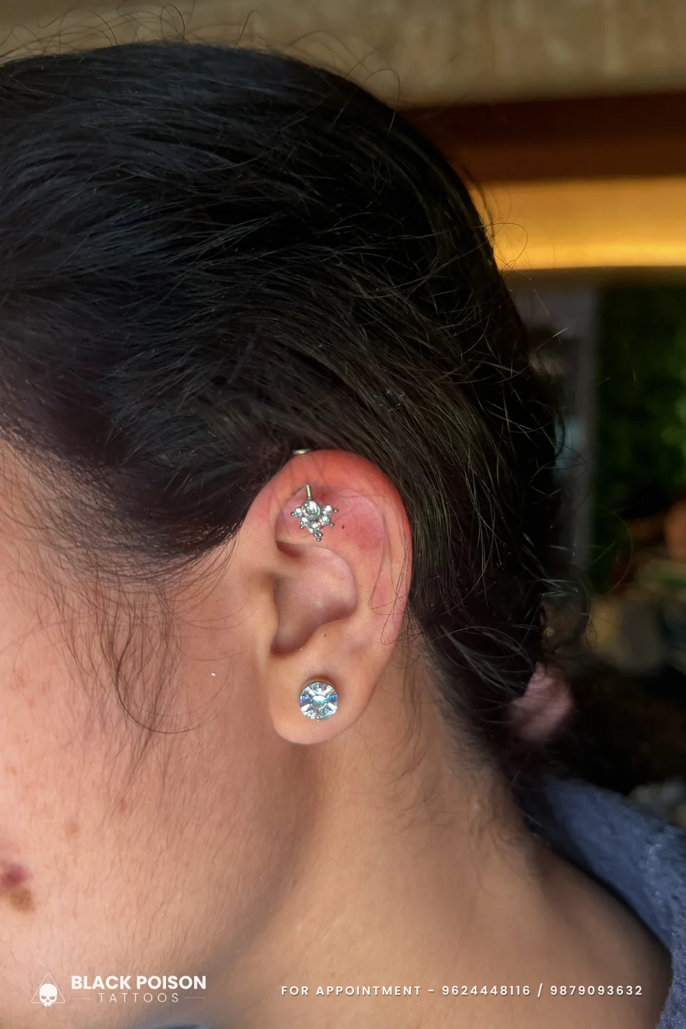 The other ear of a matched curated pair, with a crystal cluster on the upper cartilage and a single round crystal stud on the lobe