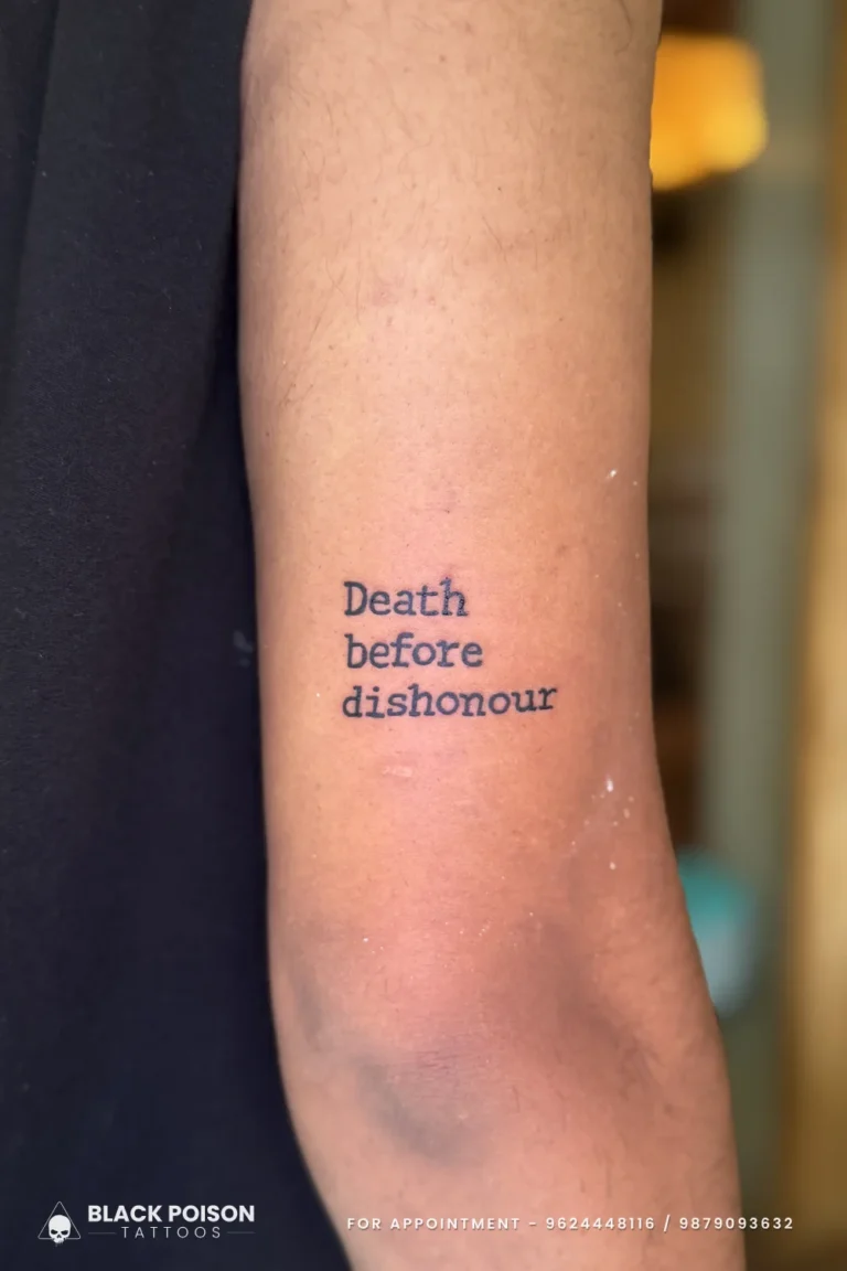 Death before dishonour in black typewriter font on the back of the upper arm at Black Poison Tattoo Studio, Ahmedabad