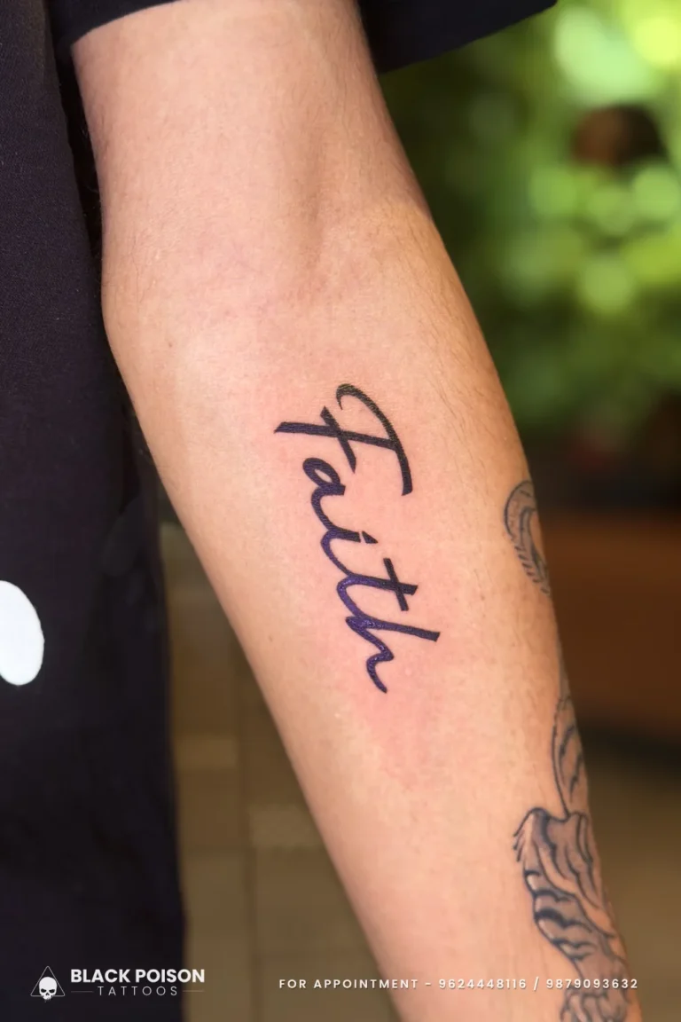 The word Faith in large bold black cursive script running down the inner forearm at Black Poison Tattoo Studio, Ahmedabad