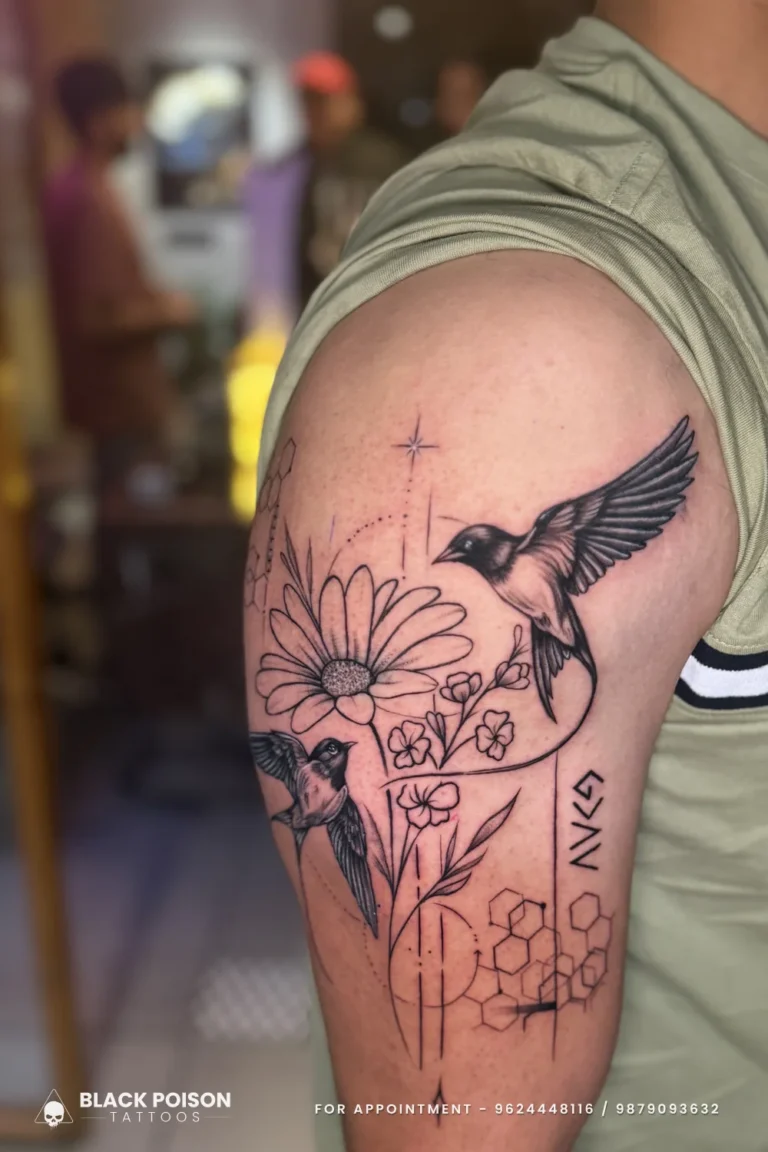 Fine line birds, daisy, wildflowers, star and honeycomb tattoo on the upper arm at Black Poison Tattoo Studio, Ahmedabad
