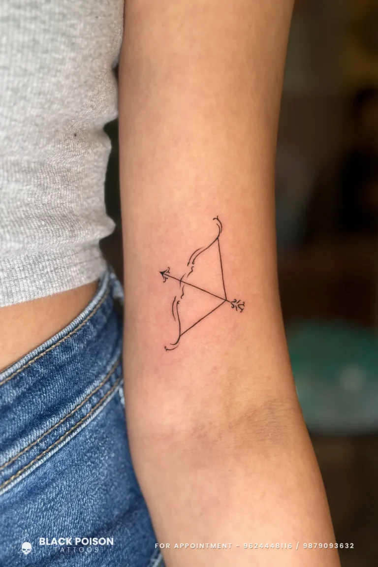 Fine line bow and nocked arrow pointing forward on the inner upper arm at Black Poison Tattoo Studio, Ahmedabad