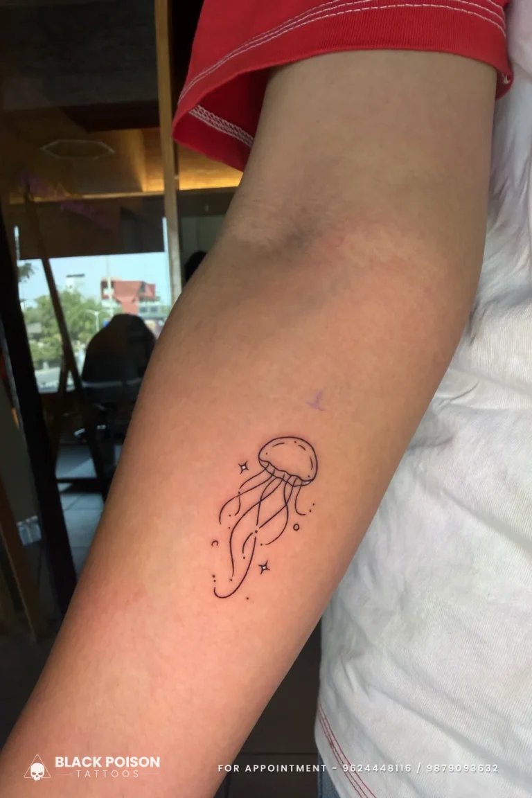 Fine line jellyfish with trailing tentacles and sparkles on the inner upper arm at Black Poison Tattoo Studio, Ahmedabad