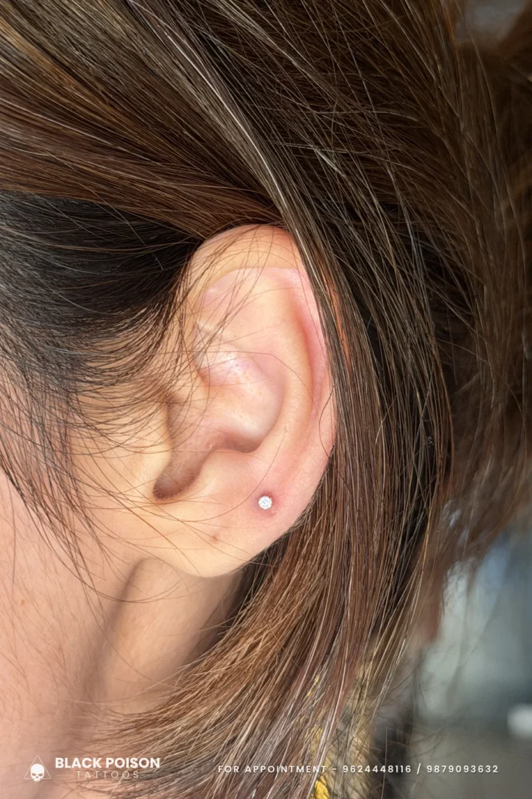 Single small crystal stud in a freshly pierced ear lobe, a classic first lobe piercing at Black Poison Tattoo Studio, Ahmedabad