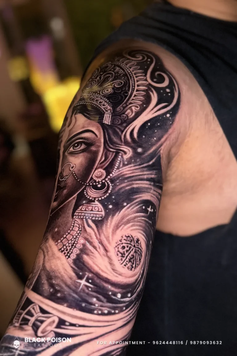 Black and grey Ganesha in an ornate crown set in a swirling galaxy on the shoulder at Black Poison Tattoo Studio, Ahmedabad