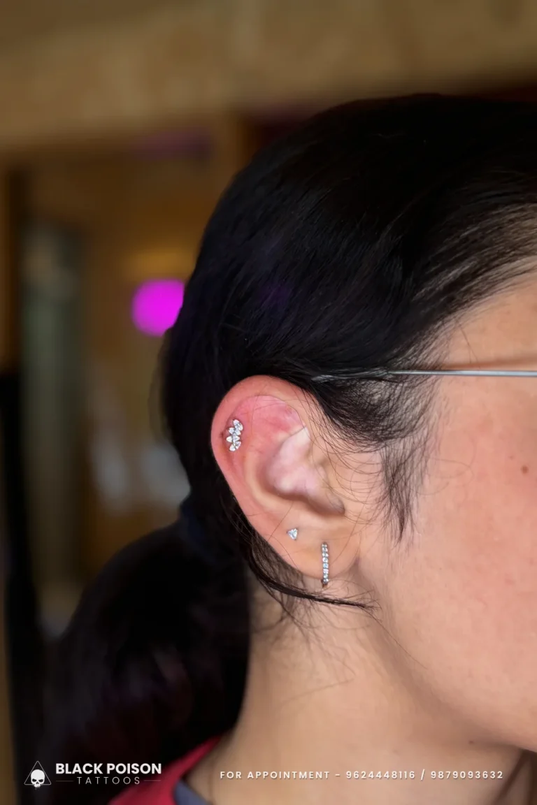Helix piercing with a jewelled flower cluster stud and a crystal lobe hoop at Black Poison Tattoo Studio, Ahmedabad