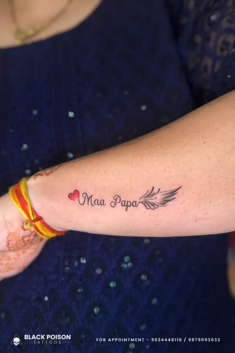 Maa Papa script tattoo with a red heart and a feathered wing on the inner forearm at Black Poison Tattoo Studio, Ahmedabad
