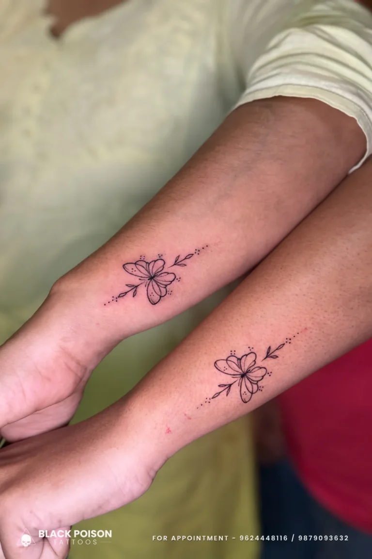 Matching fine line black butterfly tattoos with leaf sprigs on two inner forearms at Black Poison Tattoo Studio, Ahmedabad