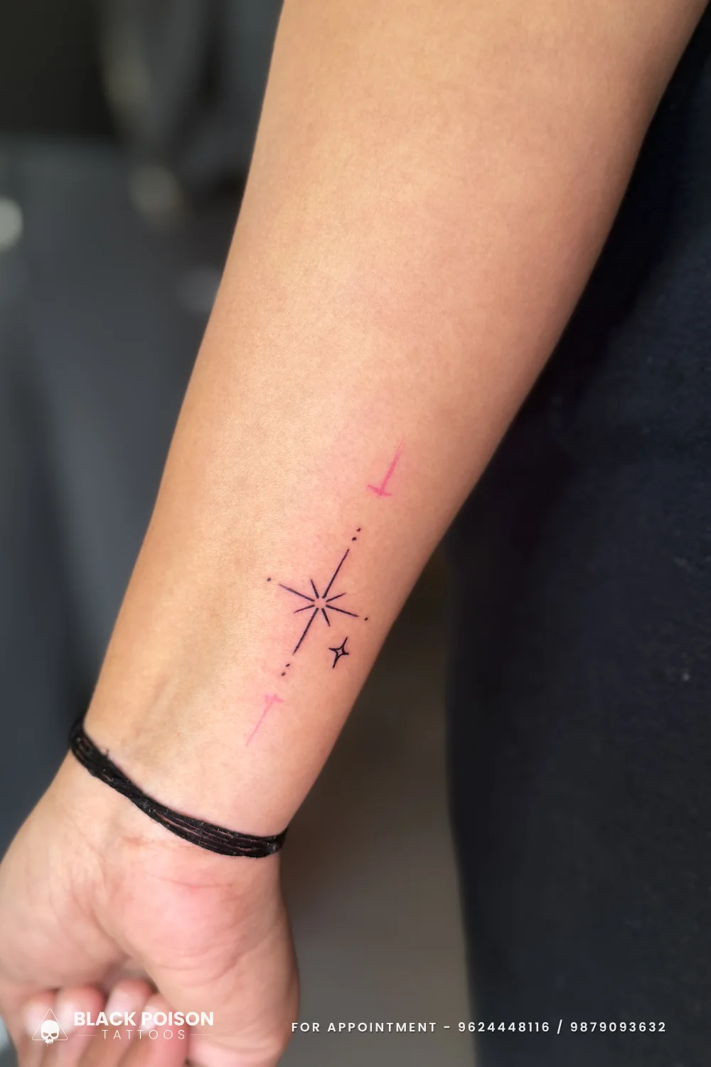 Close-up of a fine line four-point sparkle star tattoo with a dotted axis and a tiny satellite star on the inner wrist
