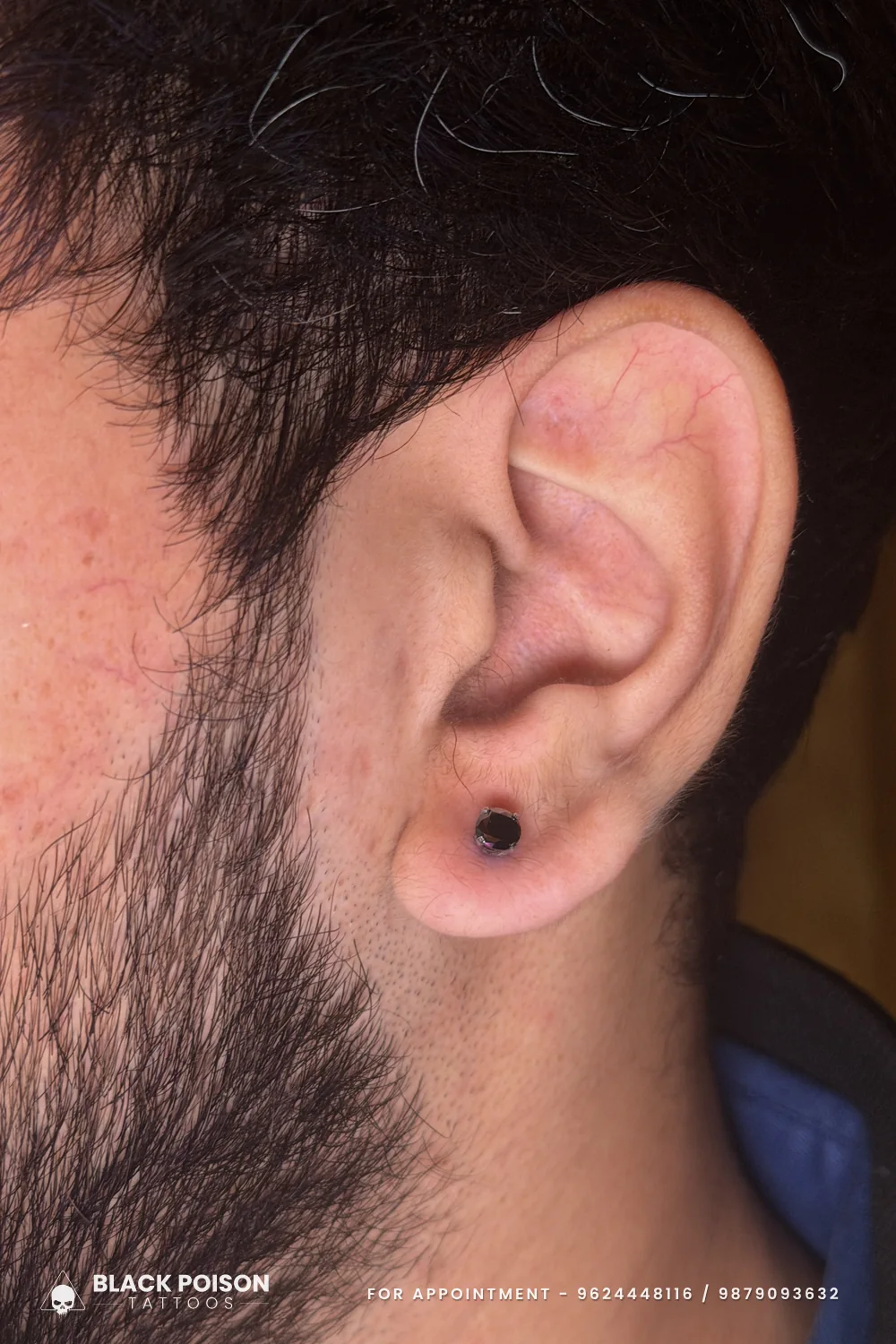 Men's ear lobe piercing with a matte black round stud, the most understated men's piercing option, on a freshly pierced lobe