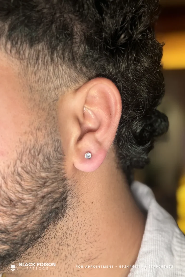 Men's ear lobe piercing with a single round crystal stud in a claw setting at Black Poison Tattoo Studio, Ahmedabad