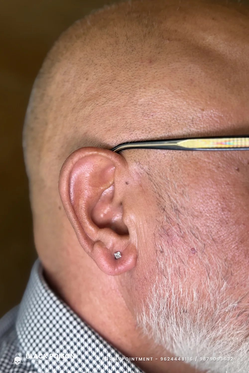 Men's ear lobe piercing with a small round crystal stud, showing that a single lobe stud suits any age