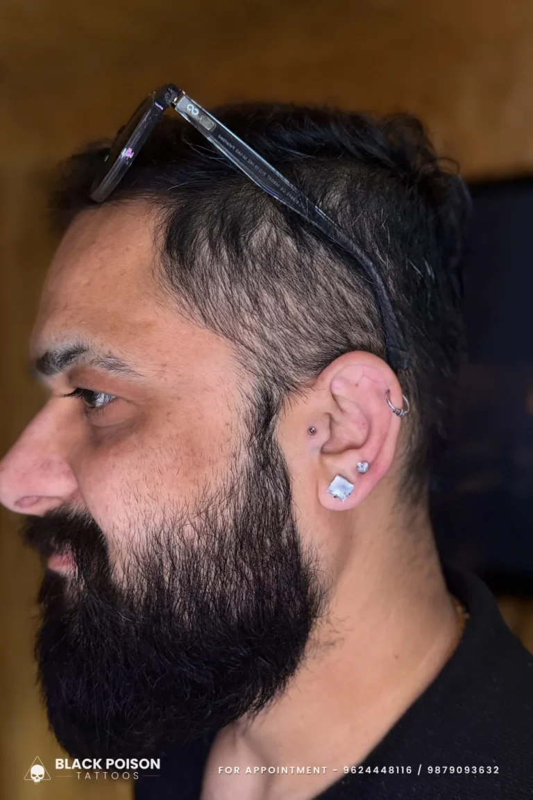 Men's tragus stud, helix ring and two crystal lobe studs in profile at Black Poison Tattoo Studio, Ahmedabad
