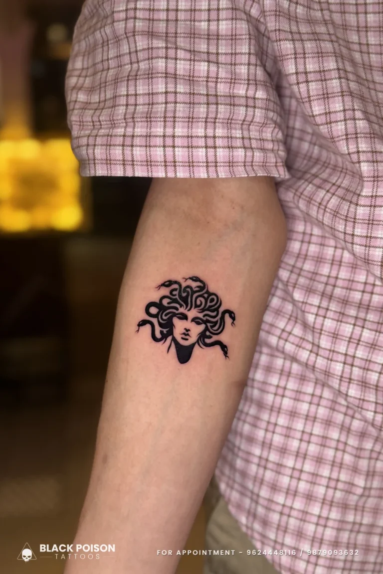 Small solid blackwork Medusa head with snake hair on the outer forearm at Black Poison Tattoo Studio, Ahmedabad