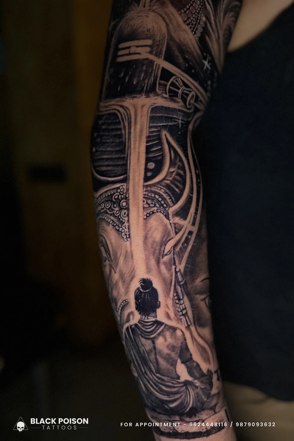 Inner forearm view of a black and grey sleeve with a trishul, damru, lotus petals and a devotee seated before a Shivling