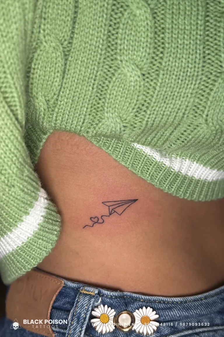 Tiny fine line paper plane with a looping heart trail on the side of the waist at Black Poison Tattoo Studio, Ahmedabad