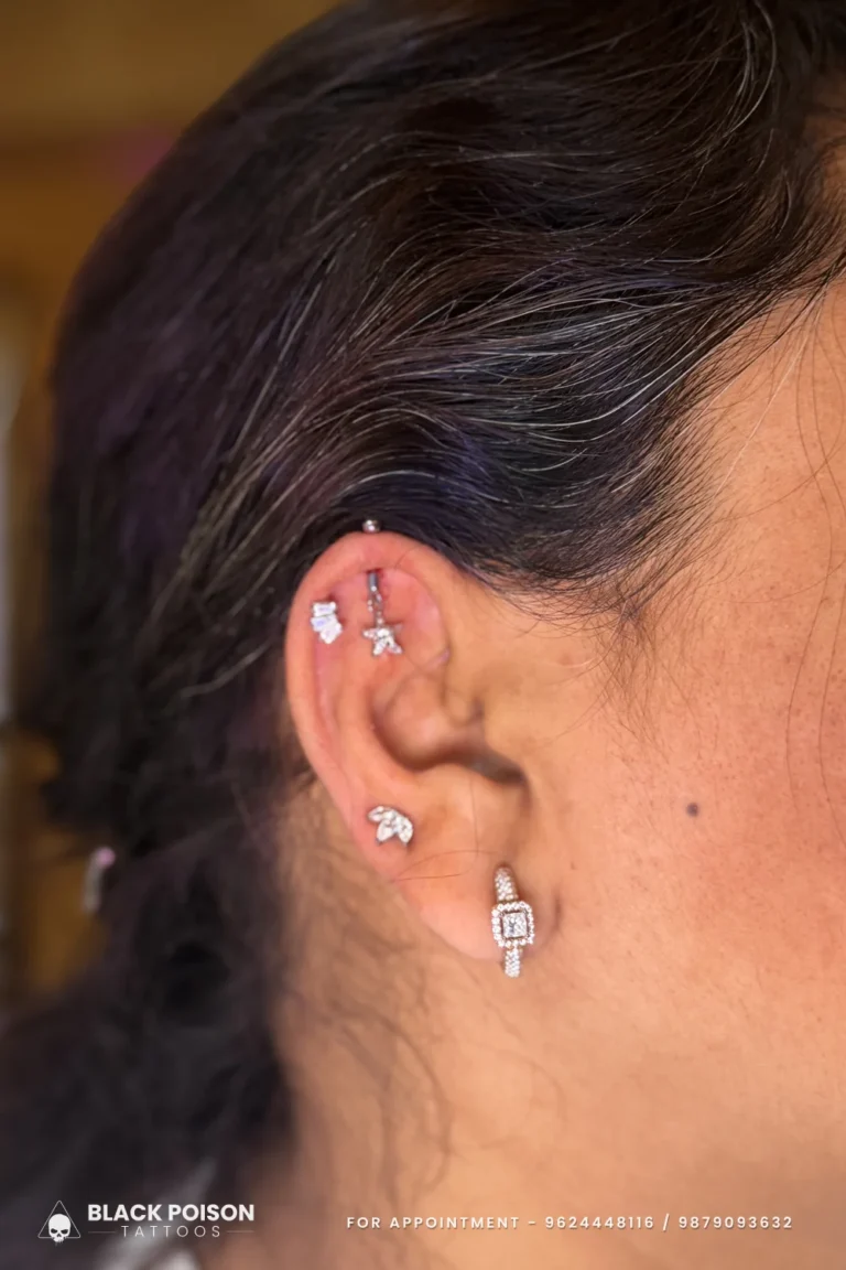 Tragus piercing with a crystal marquise leaf stud and a square crystal lobe stud at Black Poison Tattoo Studio, Ahmedabad