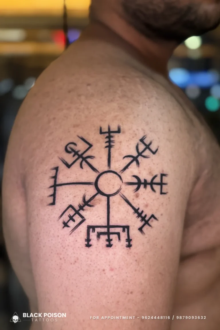 Large blackwork Vegvisir Viking compass with eight rune-tipped arms on the shoulder at Black Poison Tattoo Studio, Ahmedabad